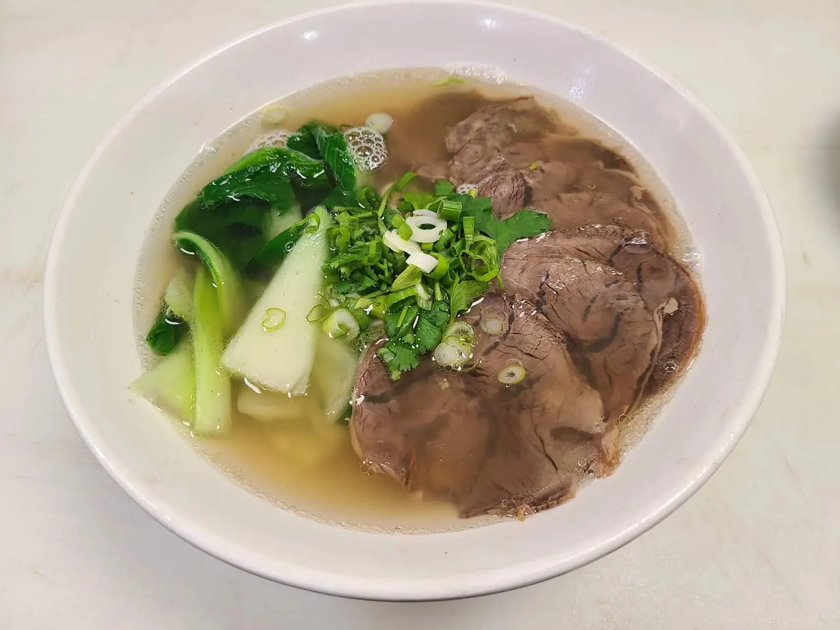 Clear beef broth with sliced beef, greens and chopped scallions at 1st Dumpling N Noodle, a Chinese Restaurant in CA